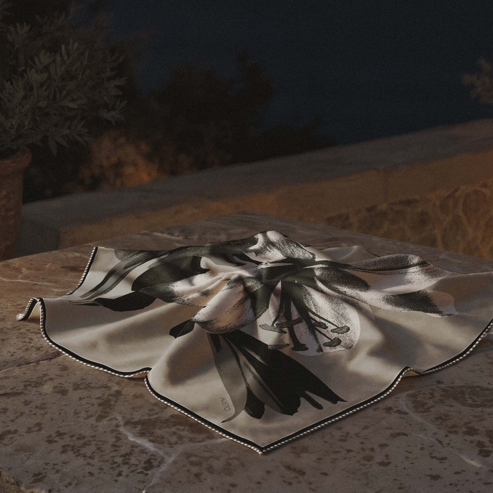 Carré de soie Alietto Fioritura 70 posé à plat sur une surface en pierre